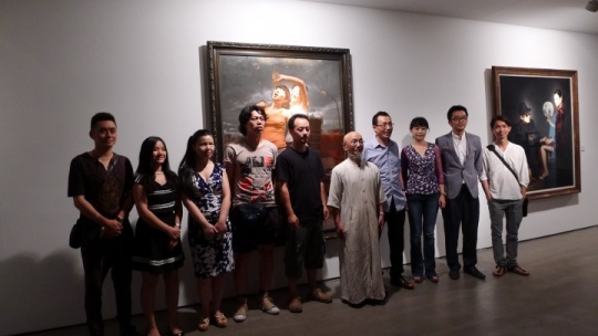 出席现场的嘉宾和部分参展艺术家合影，背景为艺术家马精虎作品《养蜂人》
