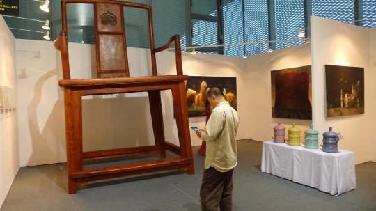 三潴画廊展位，艺术家李明铸在其作品《就是官帽椅》前
