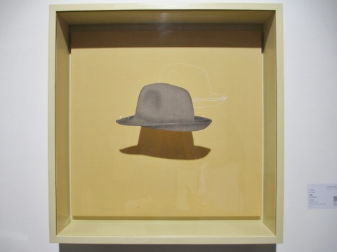 马灵丽的作品《宇宙1》，帽子的轮廓得到抽离，现于画布；它的形体得到渲染，附于玻璃。通过遮挡，光线制造的影像生成了物象的第三种形态。
