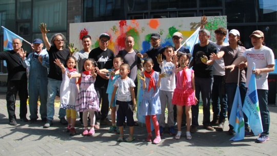 艺术家与参与活动的小朋友在共同完成了涂鸦墙前合影，掀起了活动高潮
