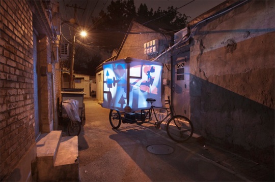 艺术家尼克·德·拉法耶（Niko de La Faye）带着一个安置在中国传统三轮车上的宇宙乾坤的象征物（八卦车）从北京到上海、再到香港，并在香港艺术博览会上举办了“M2B北京——香港”展览。图为《M2B》影像记录截图
