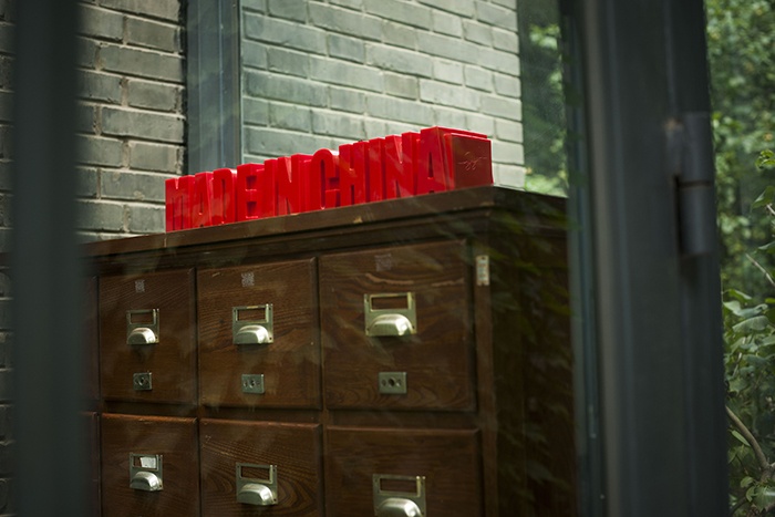 在进入居住空间的门厅，老式的药柜成为鞋柜，上面摆放着《MADE IN CHINA》的红色雕塑，侧面可以看到隋建国的签字。
