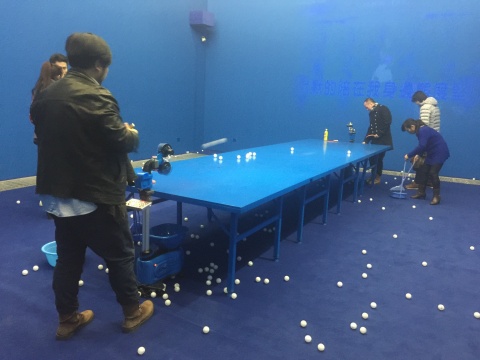 展厅内设置了乒乓球发球器，背景是夜间卡拉OK的投影
