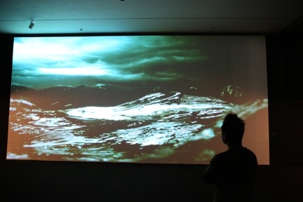 展览现场，观众在影像作品《铸浪为山》前
