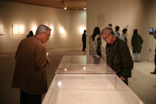 展览现场 观众在欣赏展柜里的漫画手稿