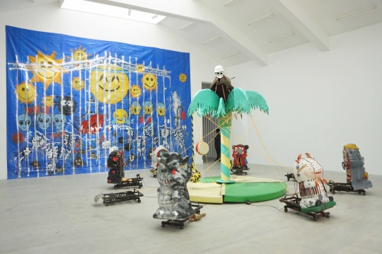 在前展厅，艺术家用偷来的椰子树和儿童摇摇车一起构建了一个阳光的欢乐世界。
