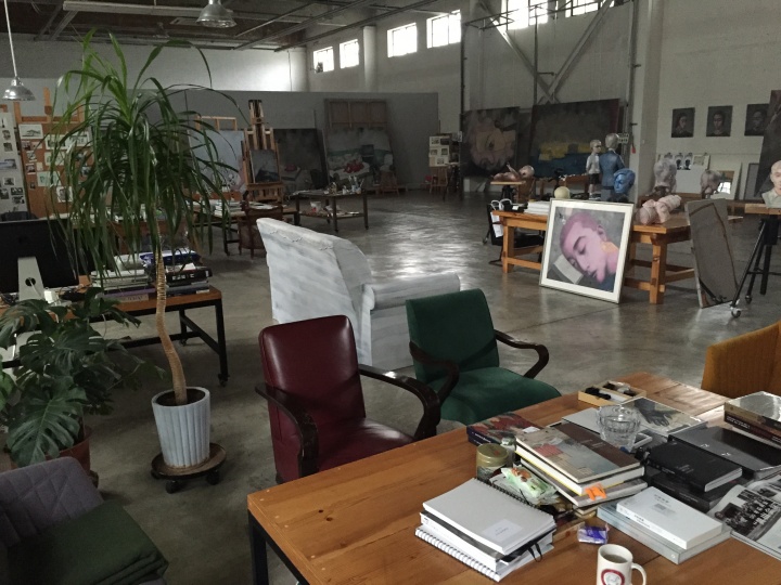 拍摄于2015年的何各庄工作室，背景处都是张晓刚正在创作的油画作品
