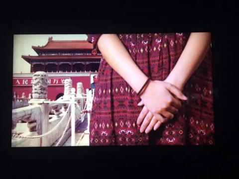 一个看似在镜头前拍照的女孩的肢体不断在画面中移动，不时的遮挡天安门和毛主席像。
