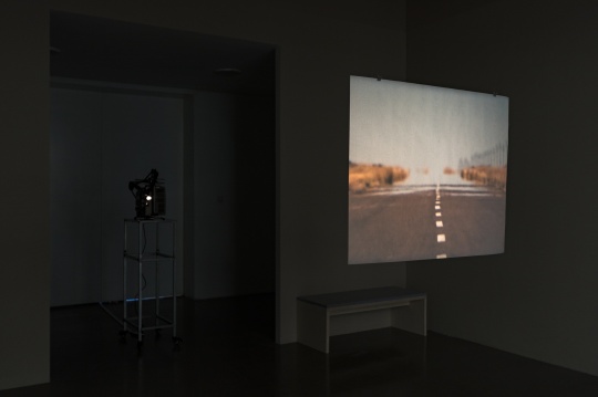 弗朗西斯·埃利斯《一个欺骗的故事，巴塔哥尼亚，阿根廷》，2003-2006年，银幕上是一条正发着热气的公路，而公路的另一边是一个闪闪发光的海市蜃楼
