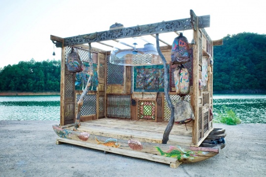 郑泽生《摩梭精灵》
420x240x300cm，装置：泸沽湖猪槽船、雕花老木板马古道老皮具、铜铃、定向音罩，2025
